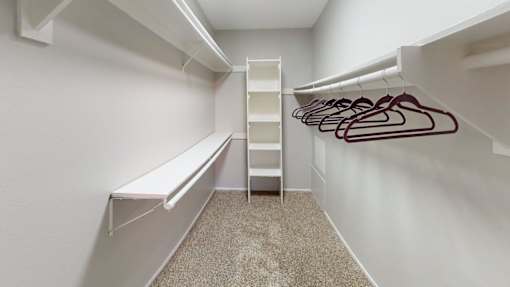 A white closet with a carpeted floor and a white bench.