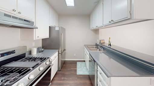 A kitchen with white cabinets and a stainless steel refrigerator.