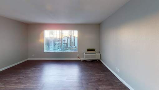 A room with wooden flooring and a window with blinds.