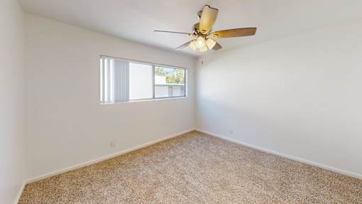 A room with a ceiling fan and carpeted floor.