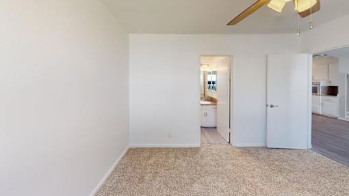 A room with a carpeted floor and a ceiling fan.