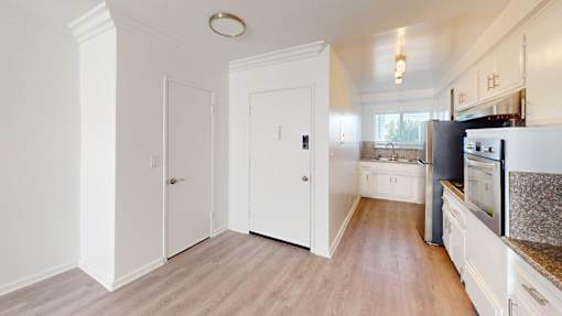 A kitchen with white cabinets and a black fridge.