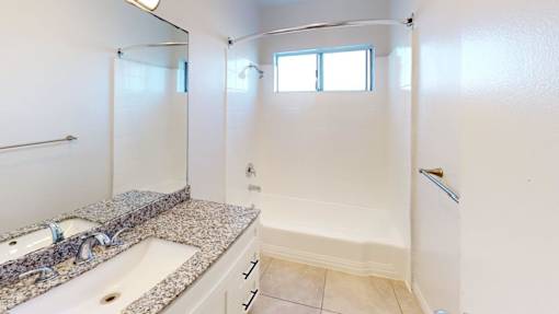 A bathroom with a granite countertop and a walk-in shower.