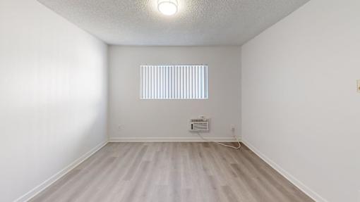 A room with a window and a white wall.