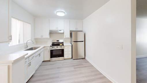 A kitchen with white cabinets and a stainless steel trash can.