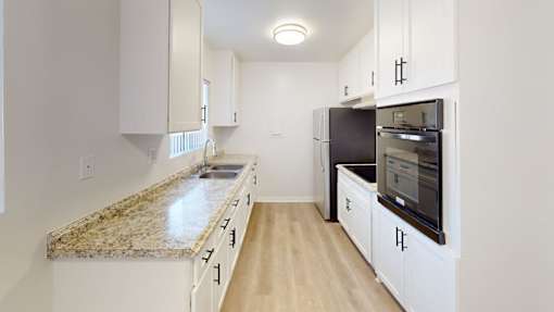 A kitchen with granite countertops and white cabinets.