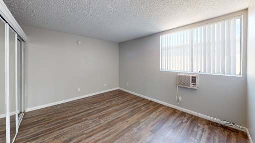 A room with wooden floors and a window with blinds.