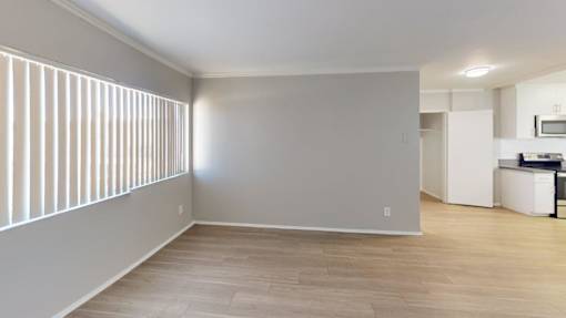 A room with wooden flooring and a window with blinds.