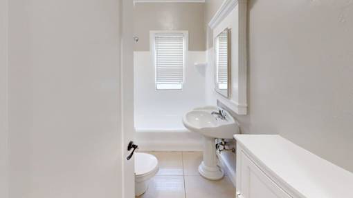 A white bathroom with a toilet, sink, and bathtub.