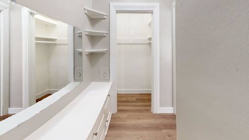 A white walk-in closet with shelves and a bench.