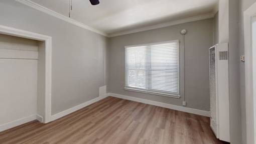 A room with wooden flooring and a window with blinds.