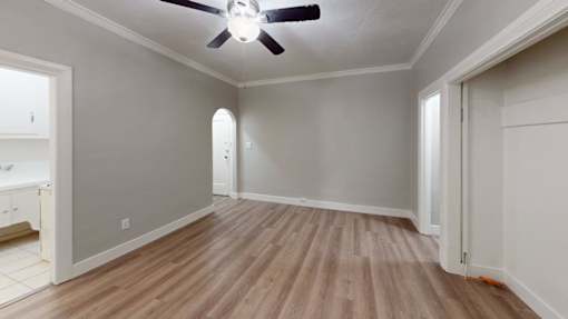 A room with a ceiling fan and wooden flooring.