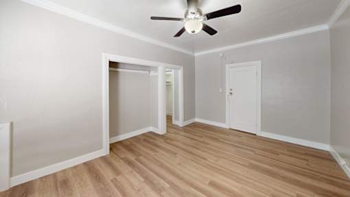A room with a ceiling fan and wooden flooring.