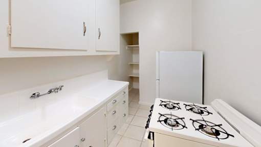 A white kitchen with a white gas stove and white cabinets.