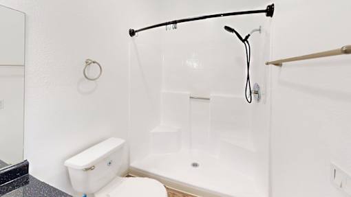 A white bathroom with a toilet, sink, and shower.