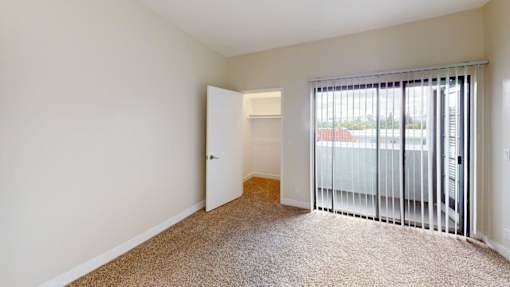 A room with a carpeted floor and a sliding glass door.