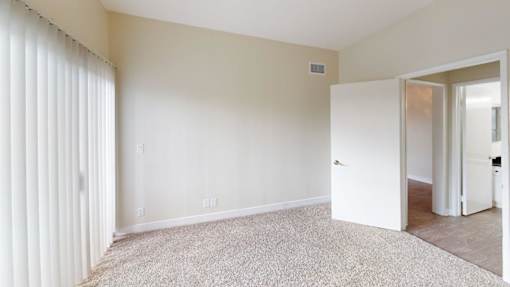 A room with a carpeted floor and a white door.