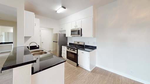 A kitchen with white cabinets and black countertops.