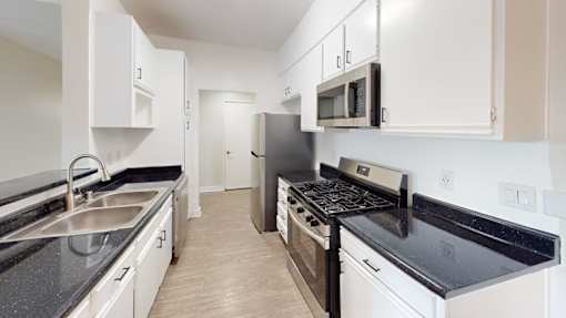 A kitchen with white cabinets and black countertops.