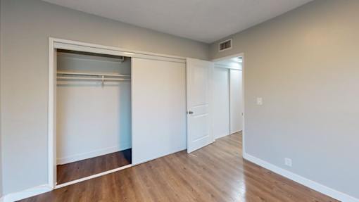 A room with a white door and a white closet with a white shelf.