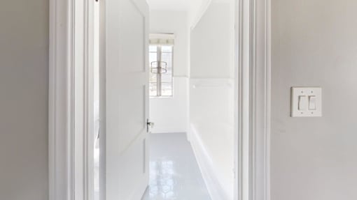 A white hallway with a light switch on the wall.