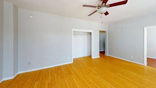 A room with a ceiling fan and wooden flooring.