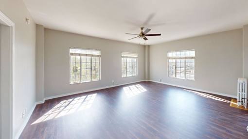 A spacious room with wooden floors and a ceiling fan.