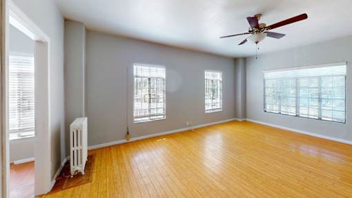 A room with a ceiling fan and wooden flooring.