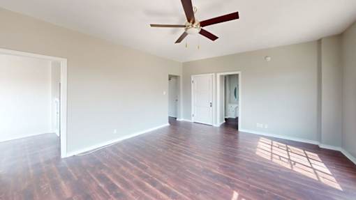 A room with a ceiling fan and wooden floors.
