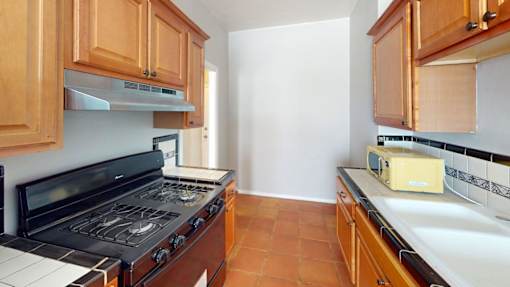 A kitchen with wooden cabinets and a black stove top oven.