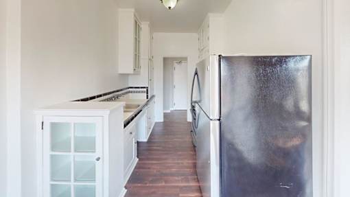 A kitchen with white cabinets and a wooden floor.