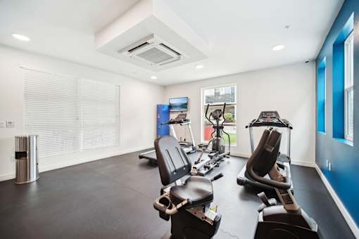 A gym with a variety of equipment including treadmills and stationary bikes.