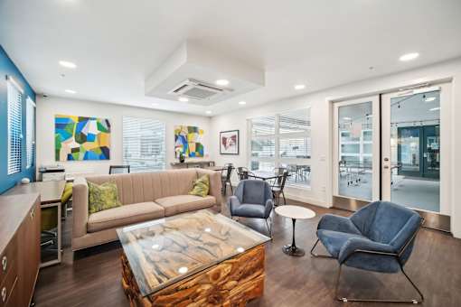 A modern living room with a glass coffee table and a blue chair.