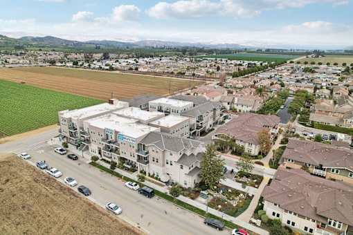 A large apartment complex is surrounded by houses and a road with cars.