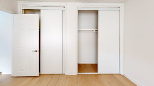 A white door is open to a room with a wooden floor.