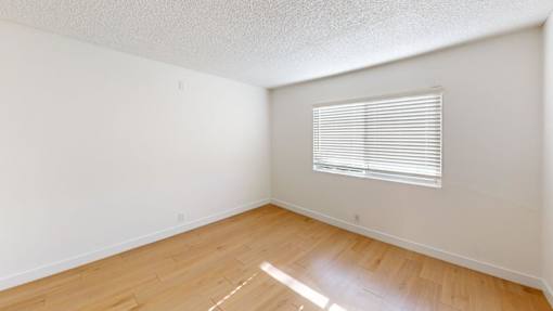 A room with a window and wooden flooring.