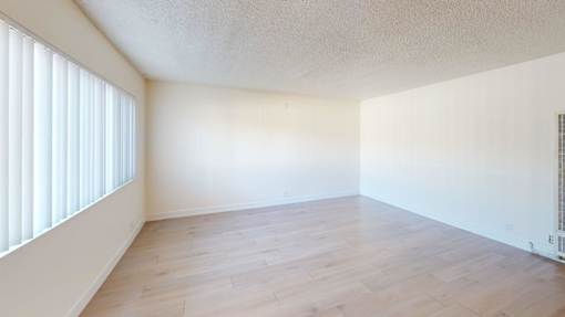 A room with wooden flooring and a window with blinds.