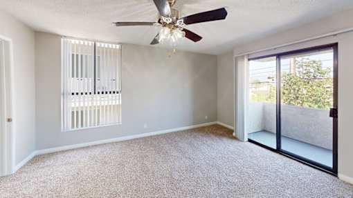 A room with a ceiling fan and sliding glass doors.