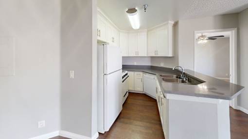 A kitchen with white cabinets and a white refrigerator.