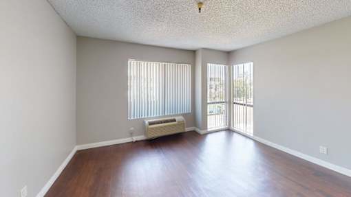 A room with wooden floors and a window with blinds.