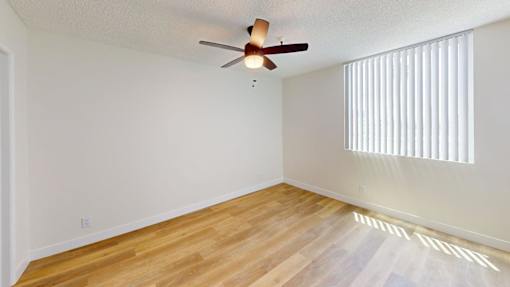 A room with a ceiling fan and wooden flooring.