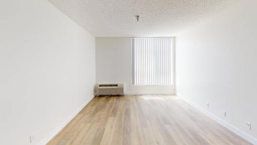 A room with wooden flooring and a window with blinds.