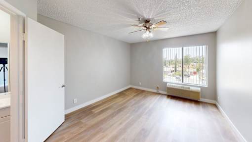 A room with a ceiling fan and a window with blinds.