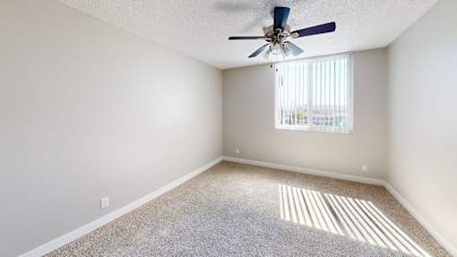 A room with a ceiling fan and carpeted floor.
