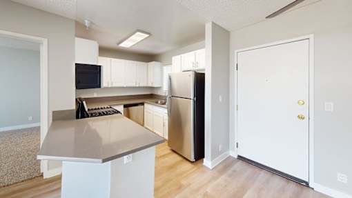 A kitchen with a white counter top and a refrigerator.