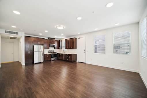A spacious kitchen with dark wood floors and white walls.
