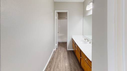 A bathroom with a white counter and wooden floor.