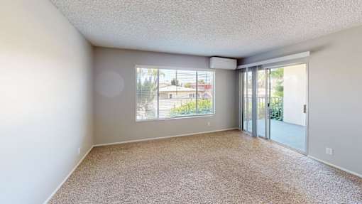 A room with a carpeted floor and a sliding glass door leading outside.