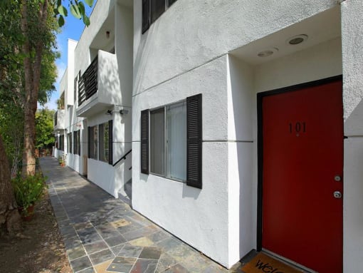 entrance to a unit with a red door and a walkway