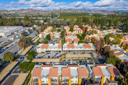 an aerial view of a neighborhood with orange roofs and a green field in the background